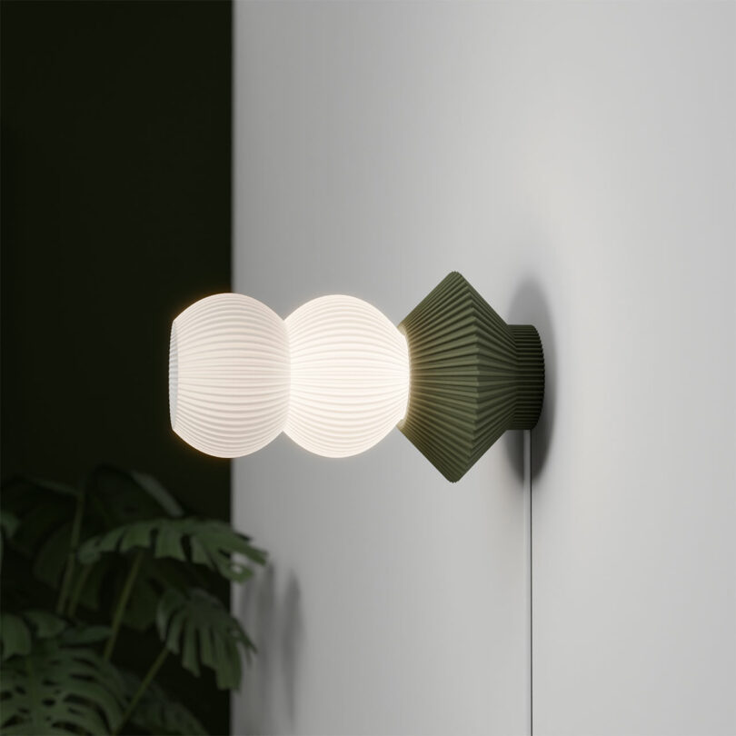 The STAK Modular Lamp features a modern wall-mounted design with ribbed glass globes and a geometric, dark green base.