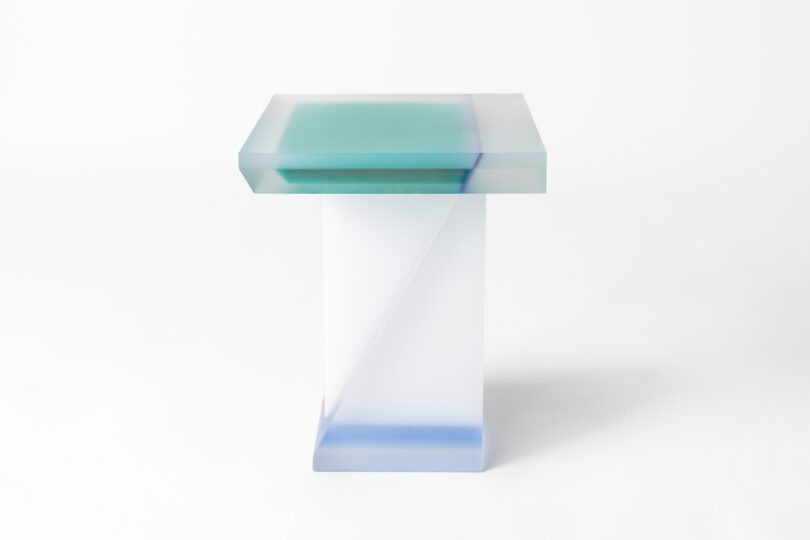 A modern, semi-transparent, rectangular table with a blue-tinted top surface, displayed against a plain white background.