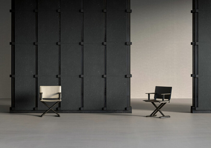 Two black director-style chairs face each other in a minimalist room with tall, dark partitions.