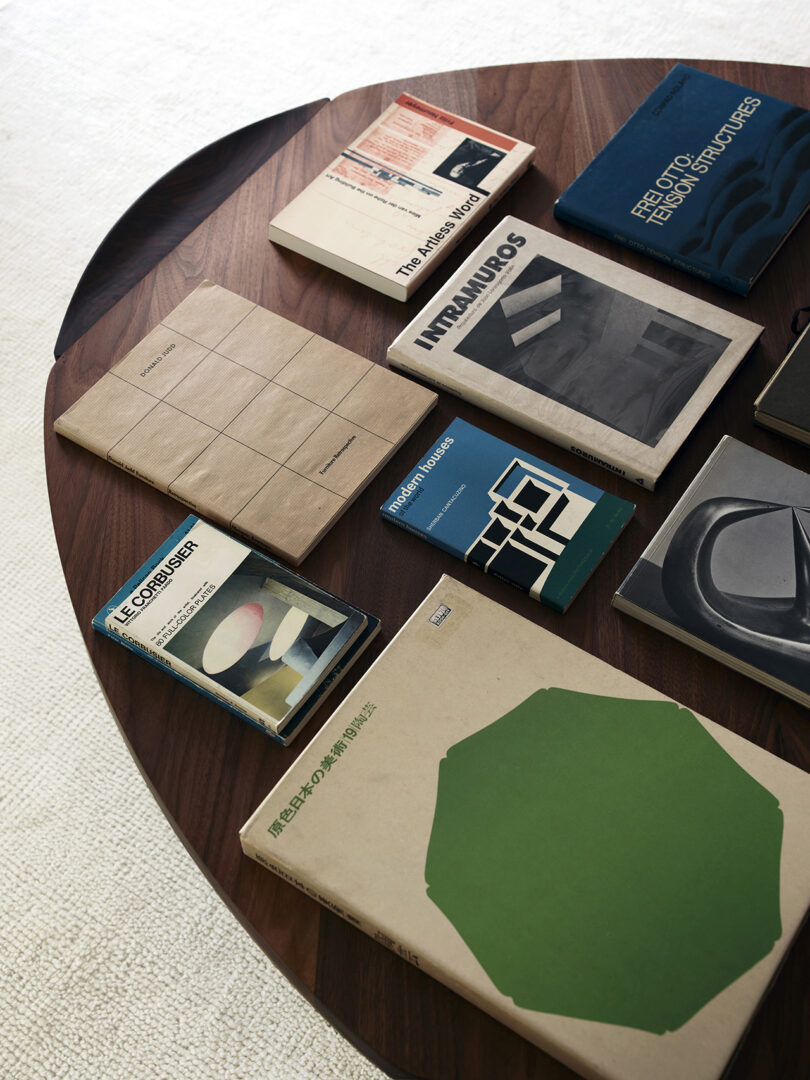 Books and magazines are neatly arranged on a wooden coffee table, featuring various covers and designs.