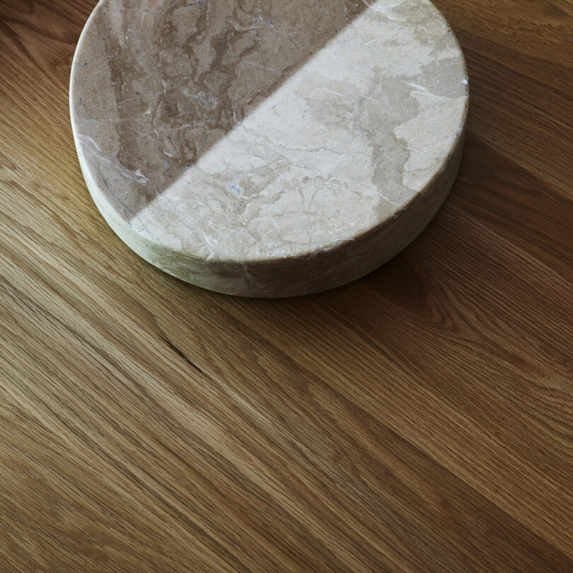 Round marble object partially in shadow on a wooden surface.