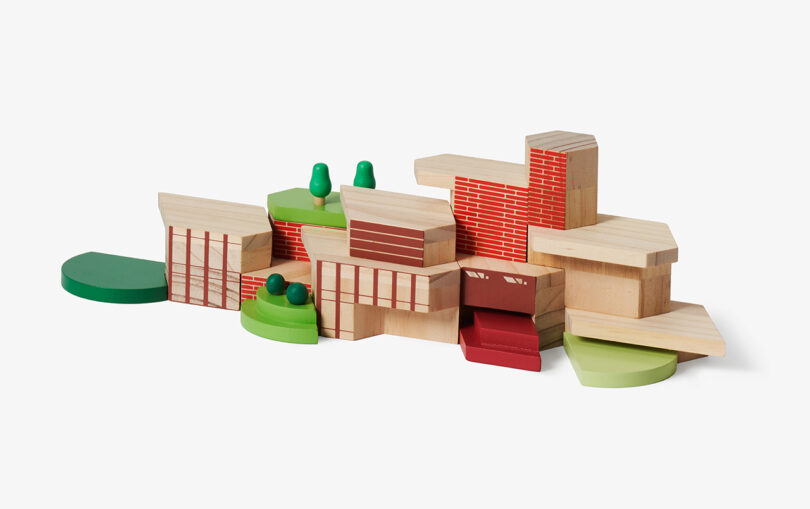 Wooden toy blocks arranged to resemble a small cityscape with various shapes, colors, and patterns, including trees and brick-like designs.