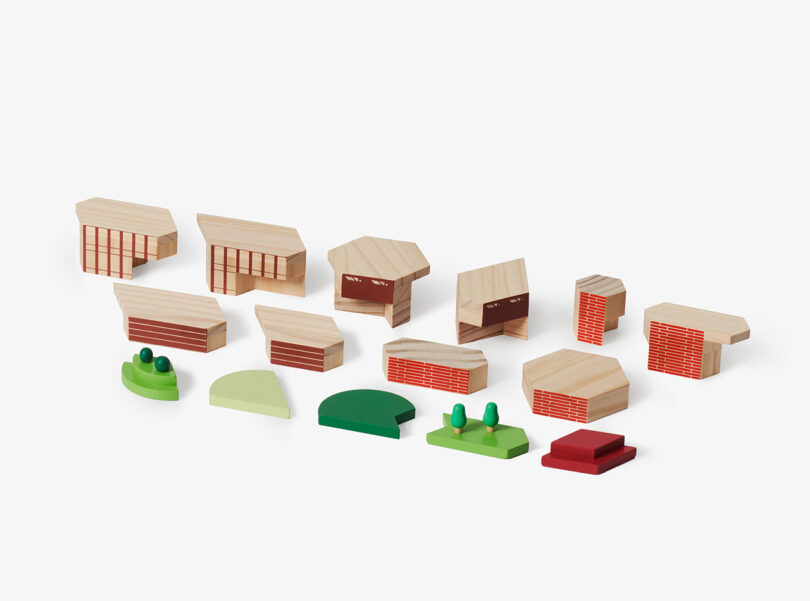 A collection of small, geometric wooden and plastic blocks resembling buildings and landscape elements arranged on a plain background.