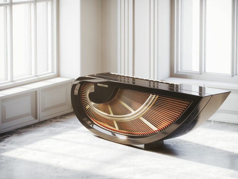 The modern, semi-circular grand piano, designed by Dan Harden, features a sleek black finish and an illuminated harp. It's beautifully situated in a bright room with large windows.