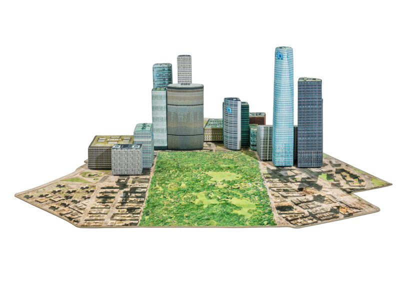 A miniature model of a city skyline features skyscrapers, a central park area, and surrounding buildings on a hexagonal base.