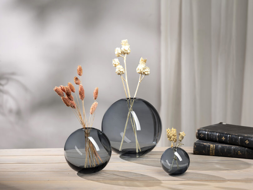 three round blue glass vases with flowers