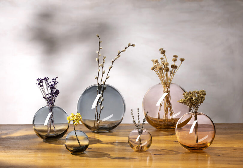 six round pink and blue glass vases with flowers