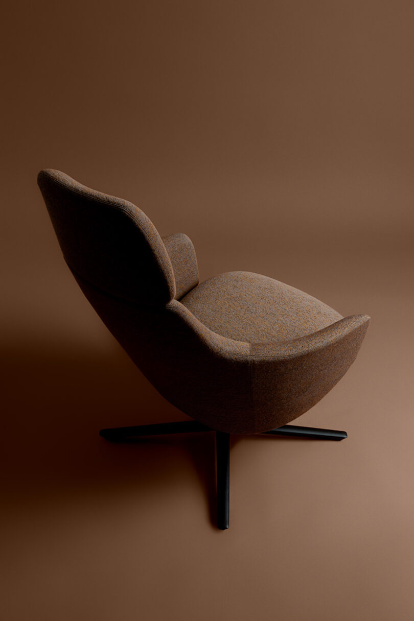 A brown, upholstered swivel chair with a modern design on a matching brown background