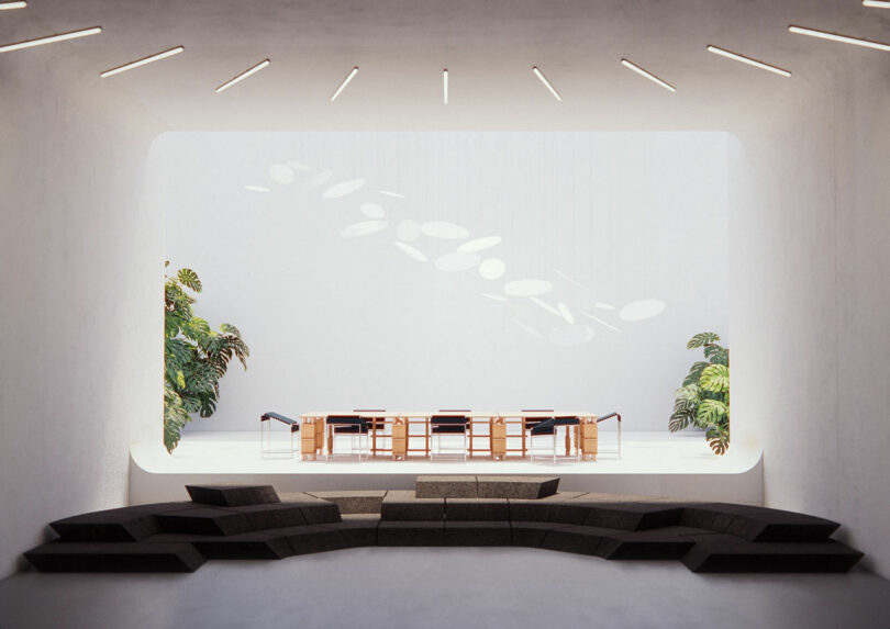 Modern meeting room with a long table, wooden chairs, and plants. The room features unique ceiling lights and tiered seating