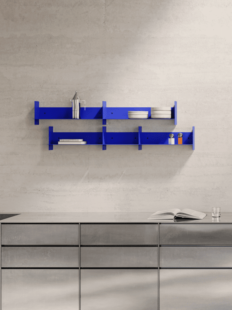 A modern kitchen with a sleek, metallic countertop and a vibrant blue wall-mounted shelf holding dishes and containers