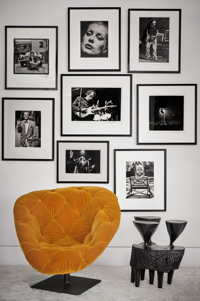 Orange chair and black side tables in front of a wall with nine framed black-and-white photos.