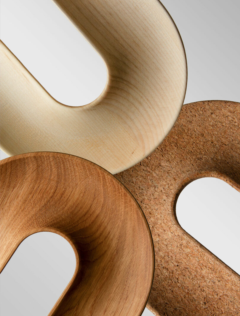 Three U-shaped wooden and cork objects overlap against a gray background, showcasing different textures and wood grains