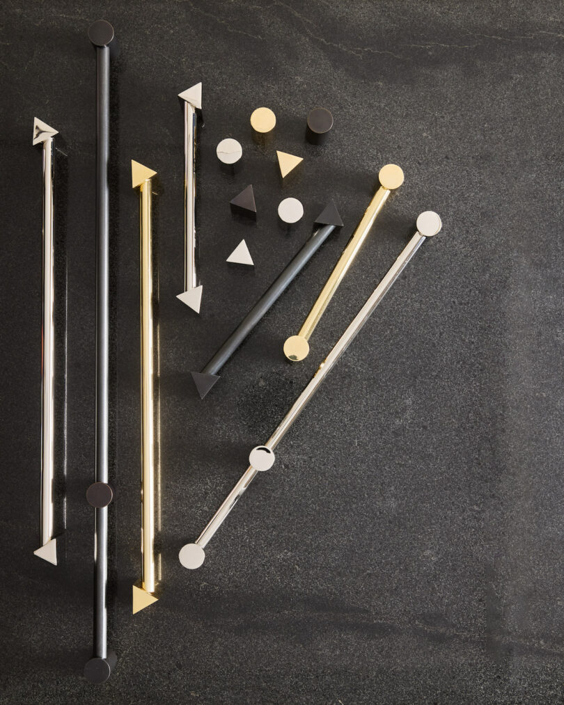 A collection of gold, silver, and black geometric hardware on a charcoal background