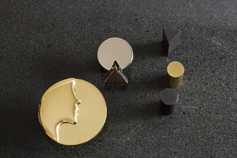 A collection of gold, silver, and black geometric hardware on a charcoal background