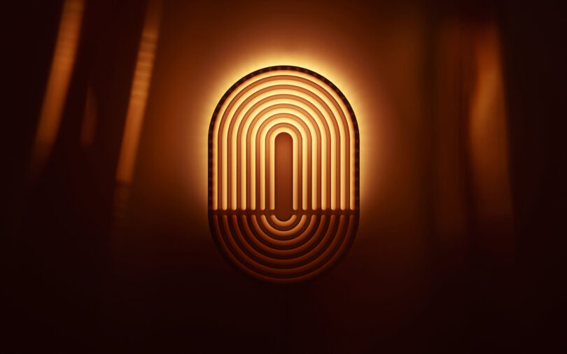 The Walmen Dumaliang-illuminated oval-shaped lamp, with its intricate concentric line pattern, stands out against a dark background, casting a warm glow