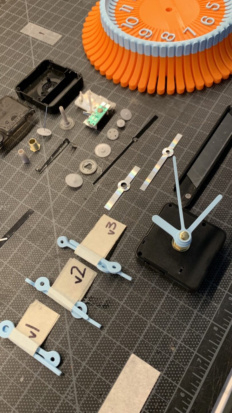 Disassembled clock parts, including hands, gears, and clock face components, are meticulously arranged on a grid-patterned surface