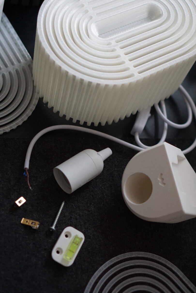 Disassembled Walmen lamp parts, including a white Dumaliang lampshade, socket, and electrical components scattered on a dark surface