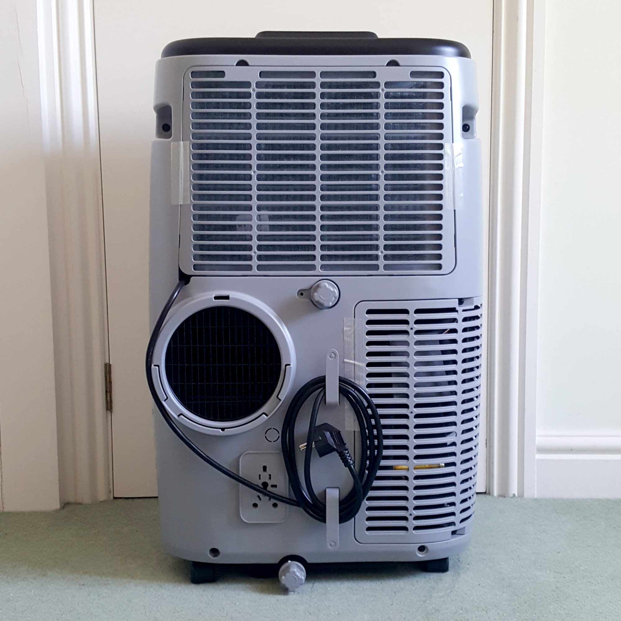 The Duux North 9K Smart Air Conditioner being unboxed in a room with a green carpet and cream walls