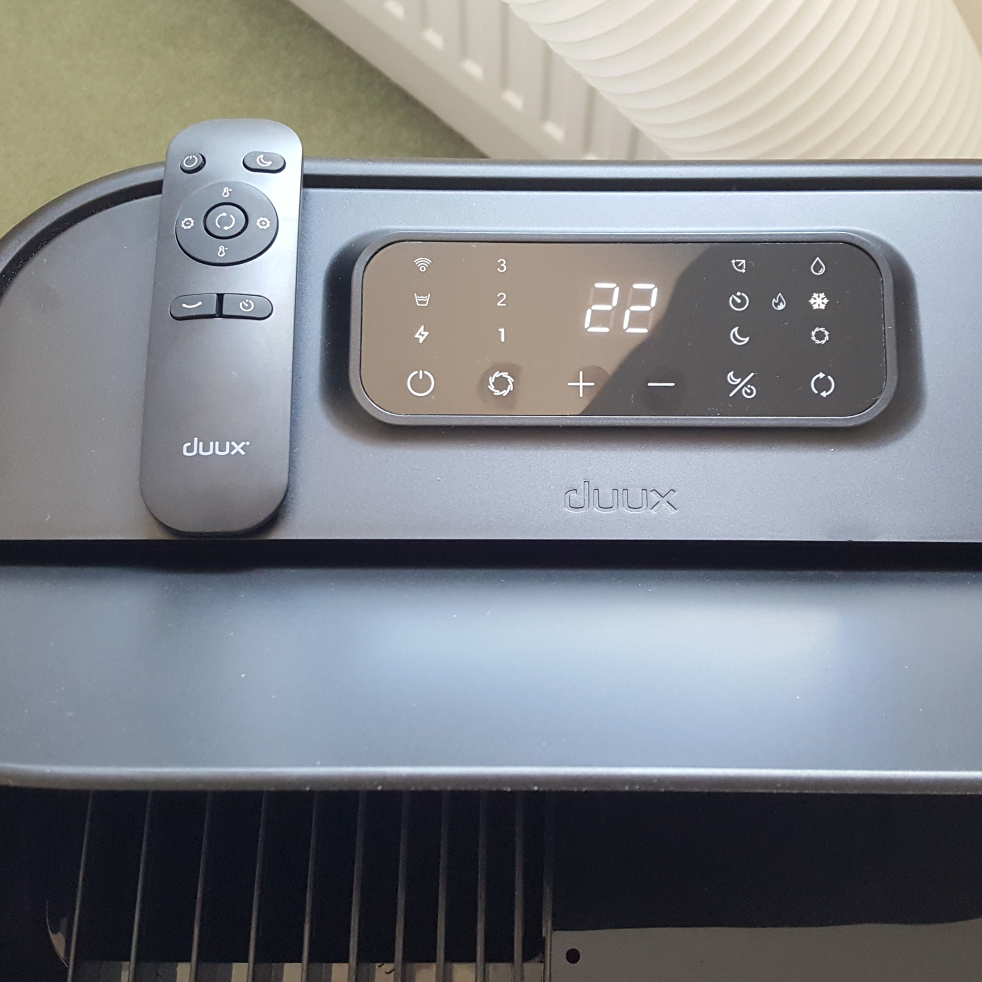The Duux North 9K Smart Air Conditioner being tested in a room with a green carpet