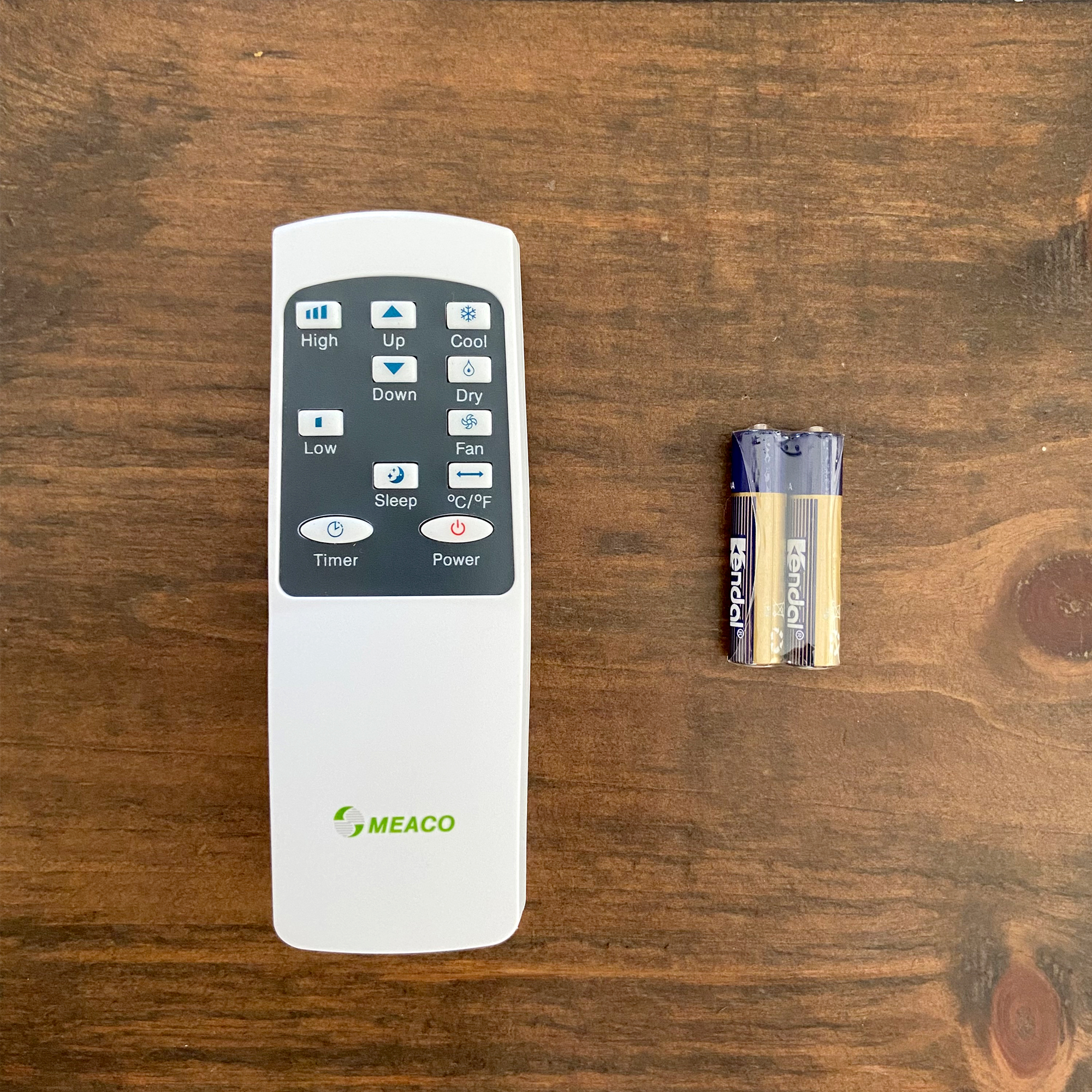 The MeacoCool MC Series 7000BTU Portable Air Conditioner  remote control and batteries on a wooden surface