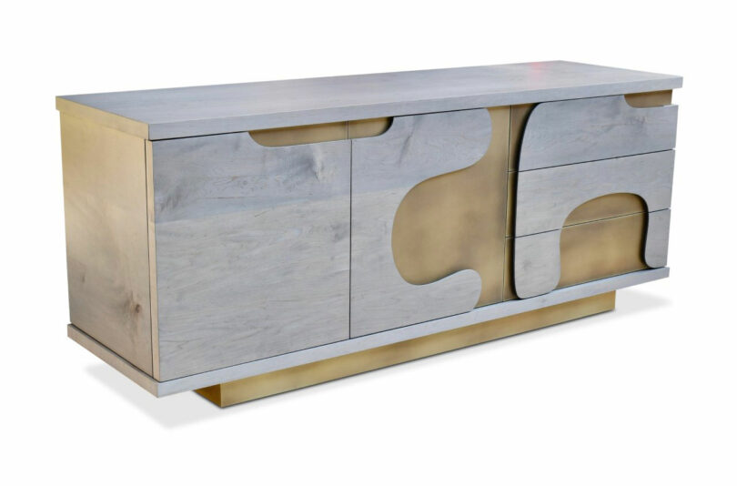 A modern sideboard by Mark Jupiter features a light wood finish, gold accents, abstract curved detailing, two doors on the left, and three drawers on the right.