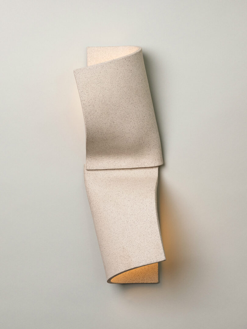 A wall-mounted Virignia Sin lighting fixture featuring a beige, folded, textured cover