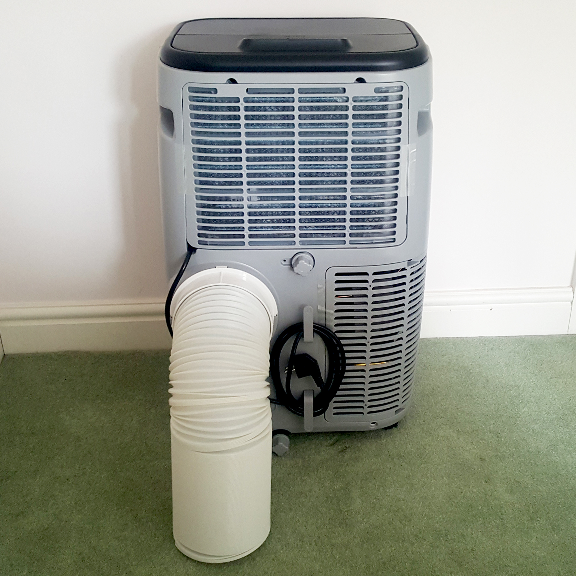 The Duux North 9K Smart Air Conditioner being tested in a room with green carpet