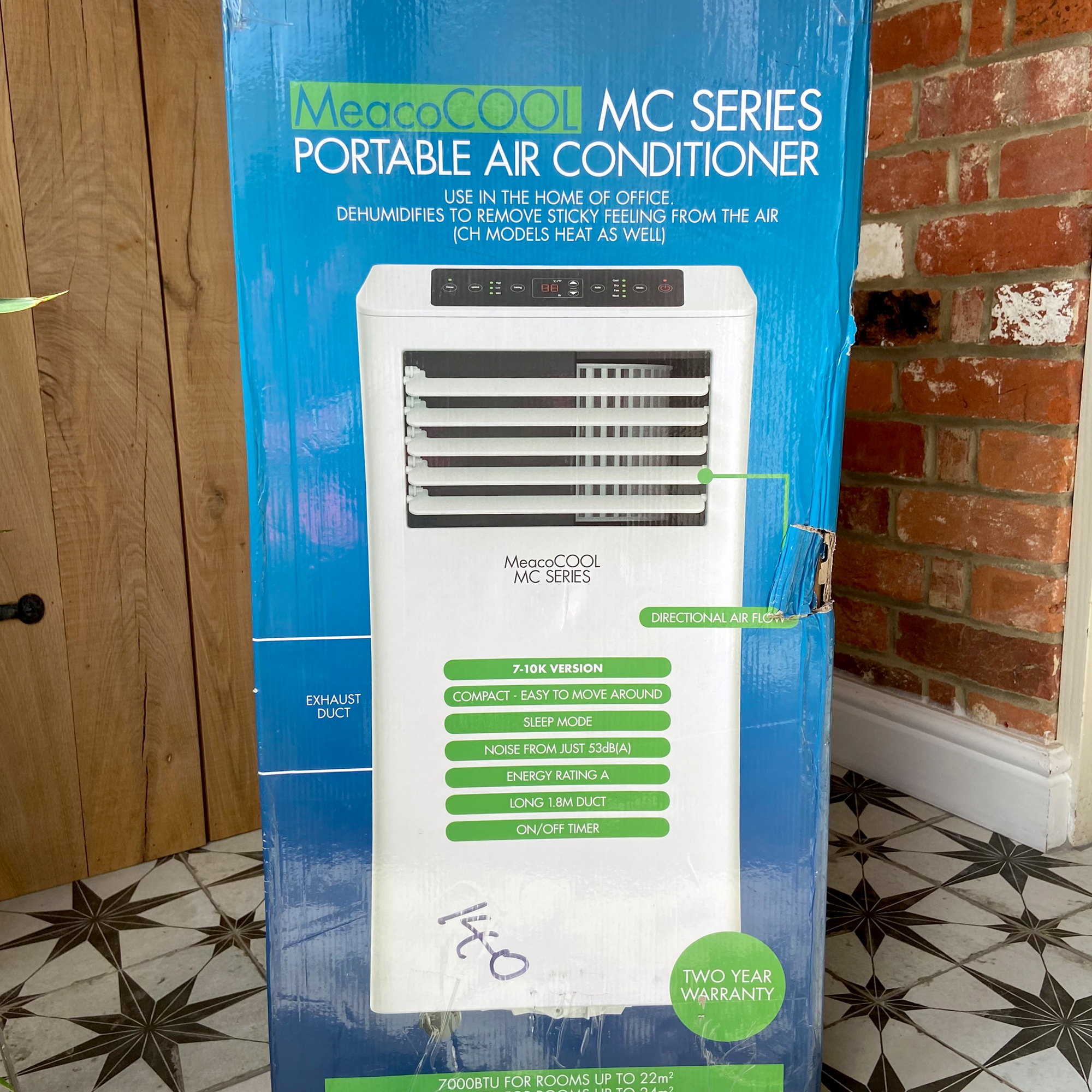 The MeacoCool MC Series 7000BTU Portable Air Conditioner  in its blue packaging box in a tiled hallway