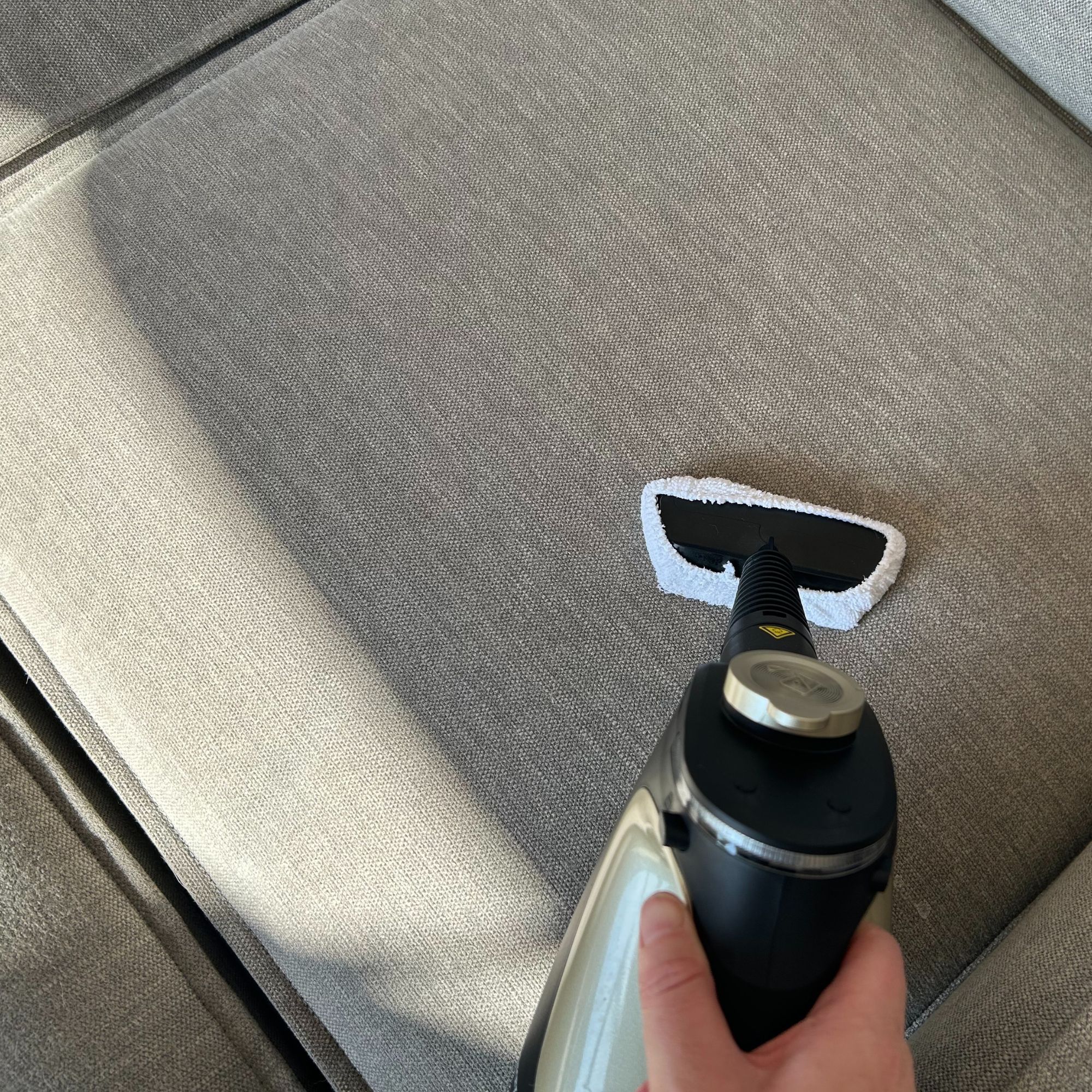 Beldray steam cleaner and upholstery attachment on grey sofa