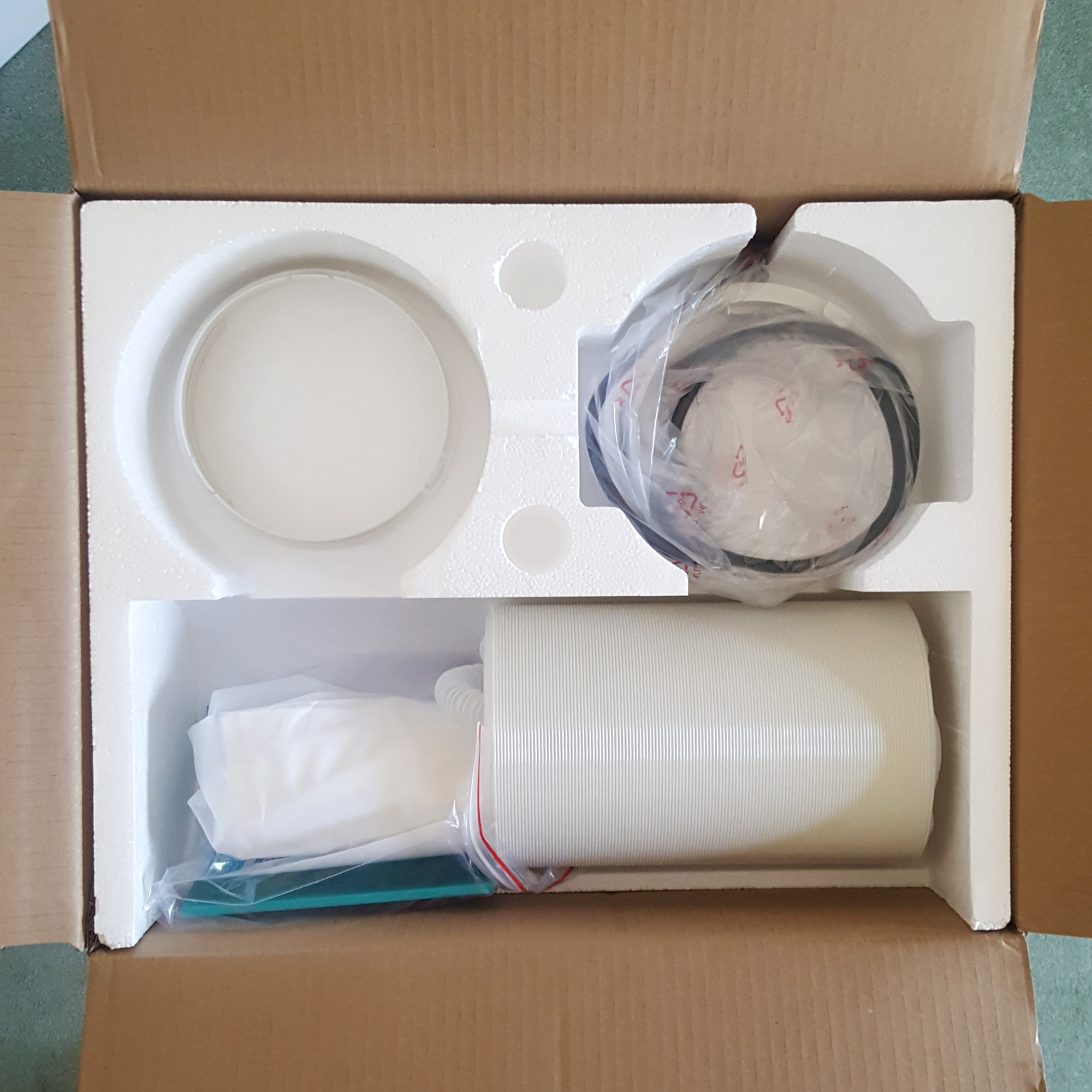 The Duux North 9K Smart Air Conditioner being unboxed in a room with a green carpet and cream walls