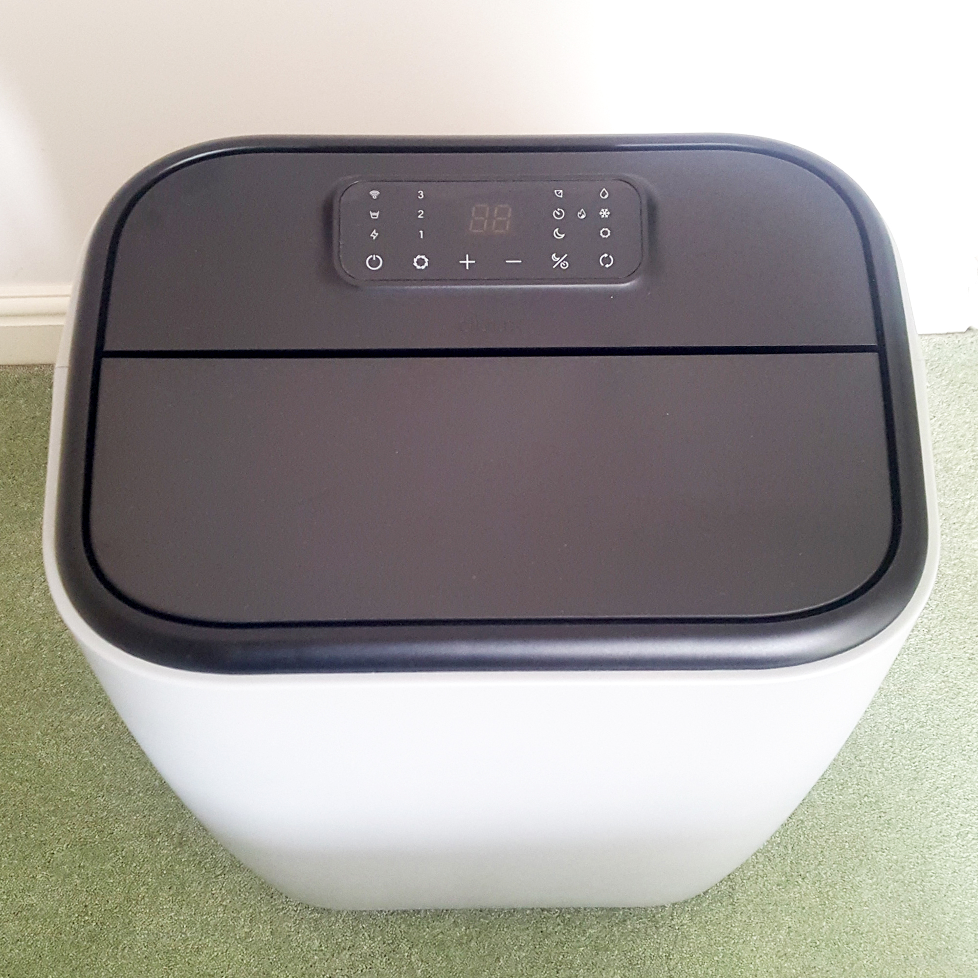 The Duux North 9K Smart Air Conditioner being tested in a room with green carpet