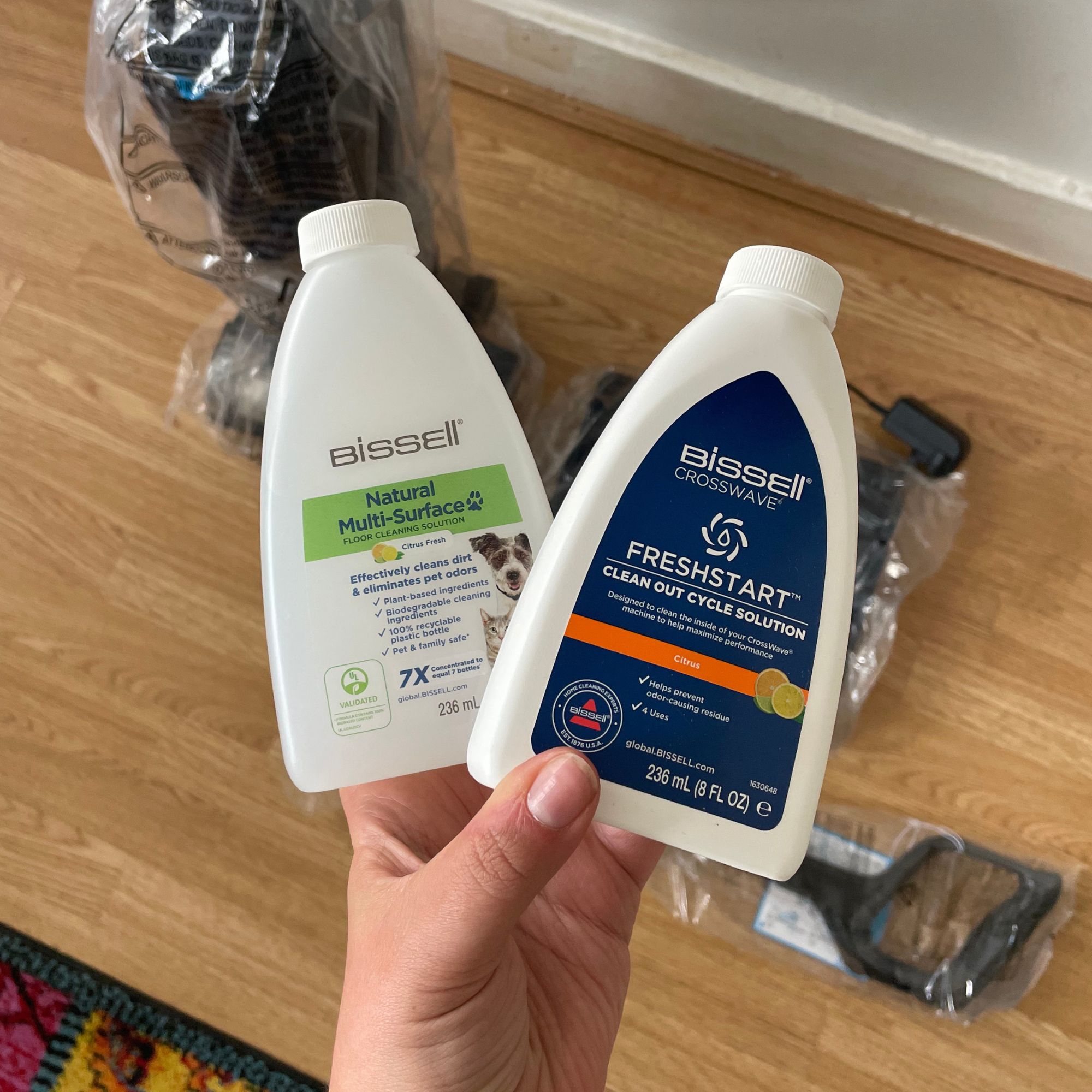 Hand holding cleaning bottles of the Bissell Crosswave Omniforce Edge 