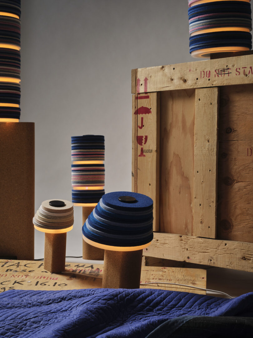 stacked lamps, some lit, are artistically arranged around a crate