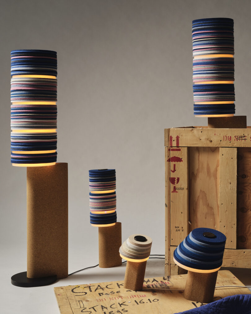 stacked lamps, some lit, are artistically arranged around a crate