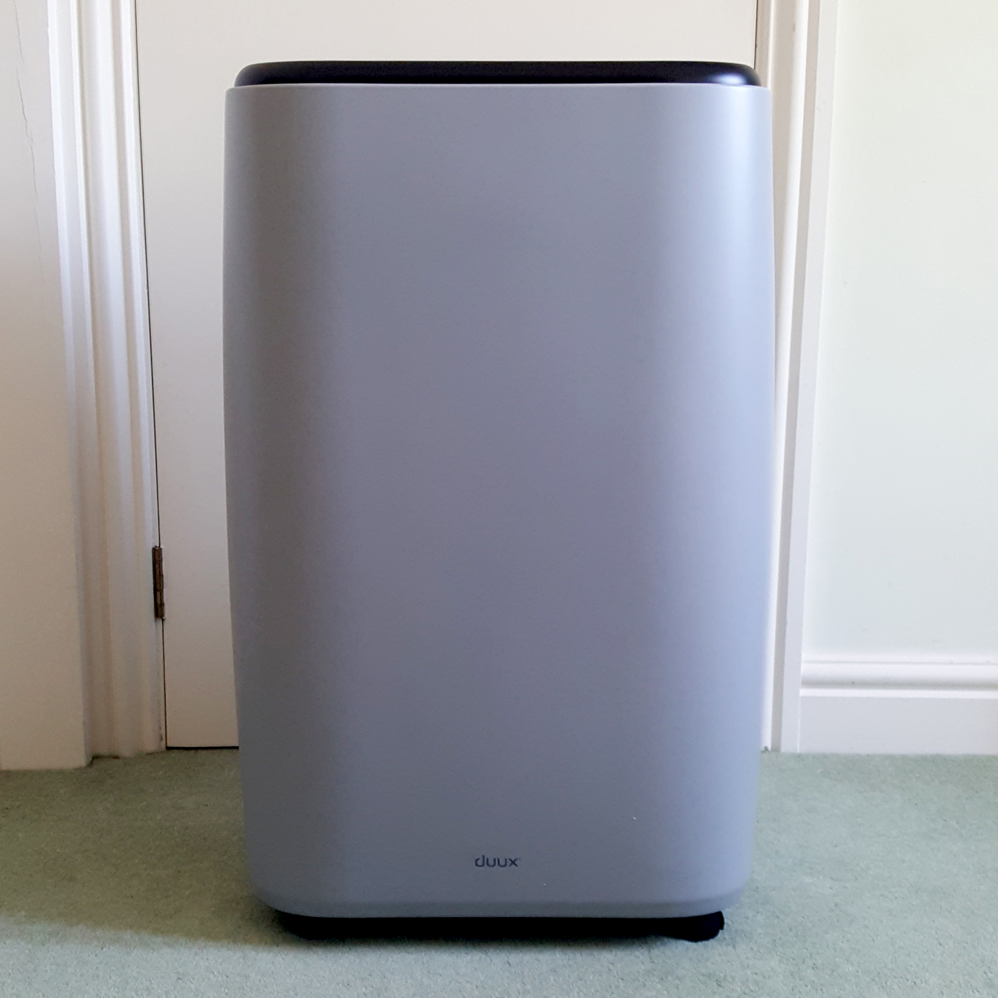 The Duux North 9K Smart Air Conditioner being unboxed in a room with a green carpet and cream walls