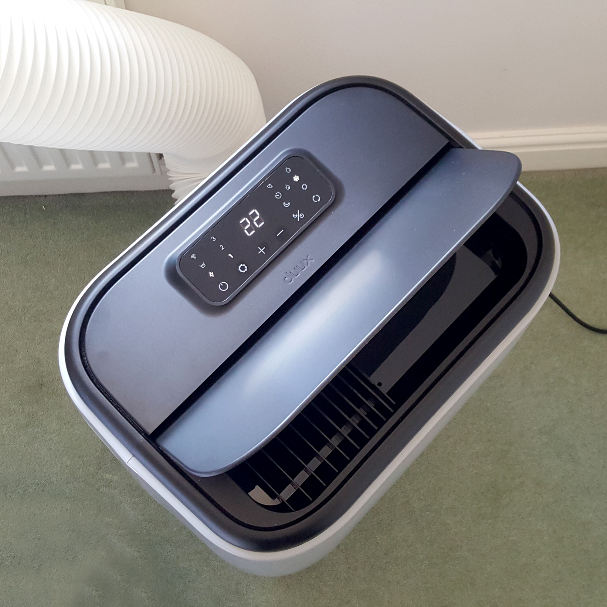 The Duux North 9K Smart Air Conditioner being tested in a room with a green carpet