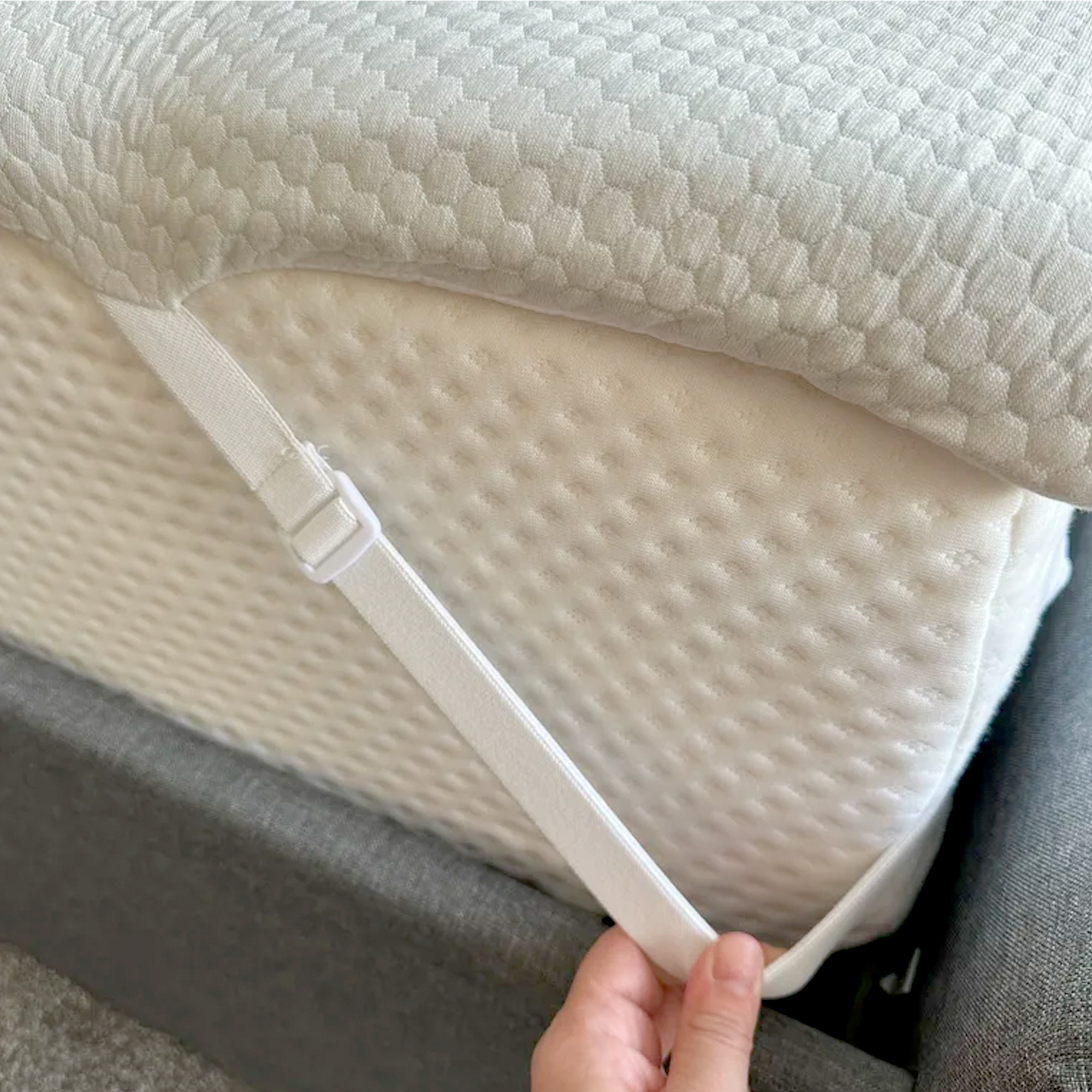 The corner of the Panda Topper with a hand holding one of its adjustable elasticated straps