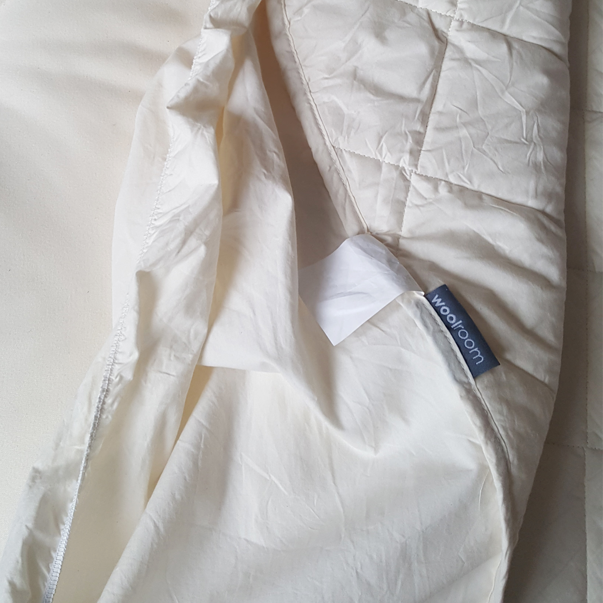 The Woolroom Deluxe Washable Wool Mattress Protector being tested on a mattress in a bedroom